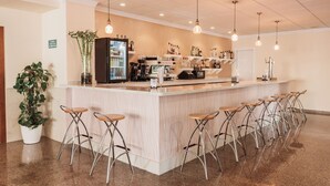A bar area with a counter, stools, and hanging lights. - Hotel Camposol (Benidorm)