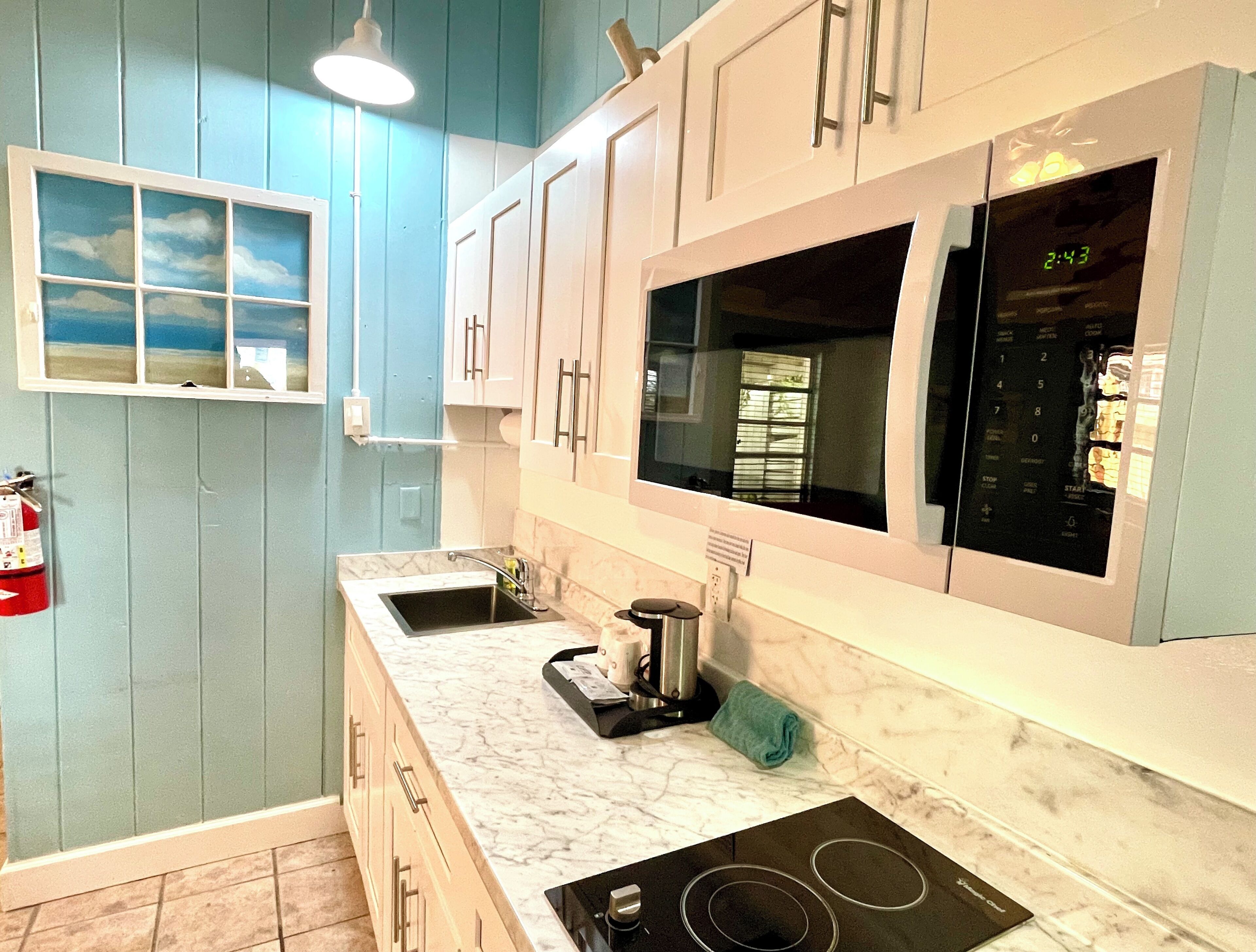 A kitchen with a sink, stove, and microwave.