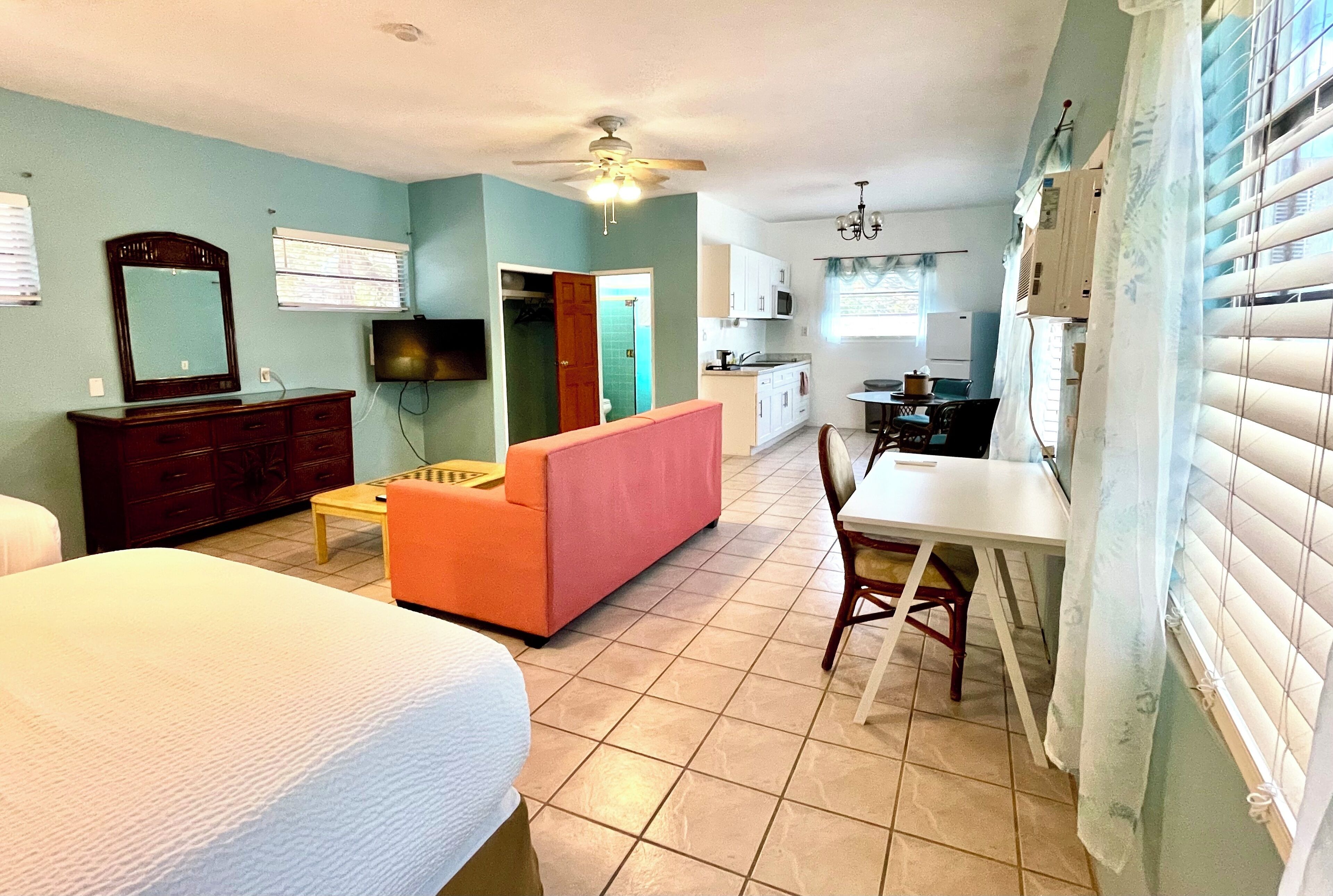 Una habitación de hotel con cama, sofá, mesa de comedor y kitchenette.