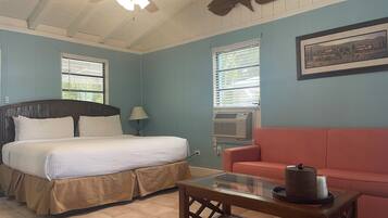 A room with a bed, a pink sofa, a coffee table, and a ceiling fan.