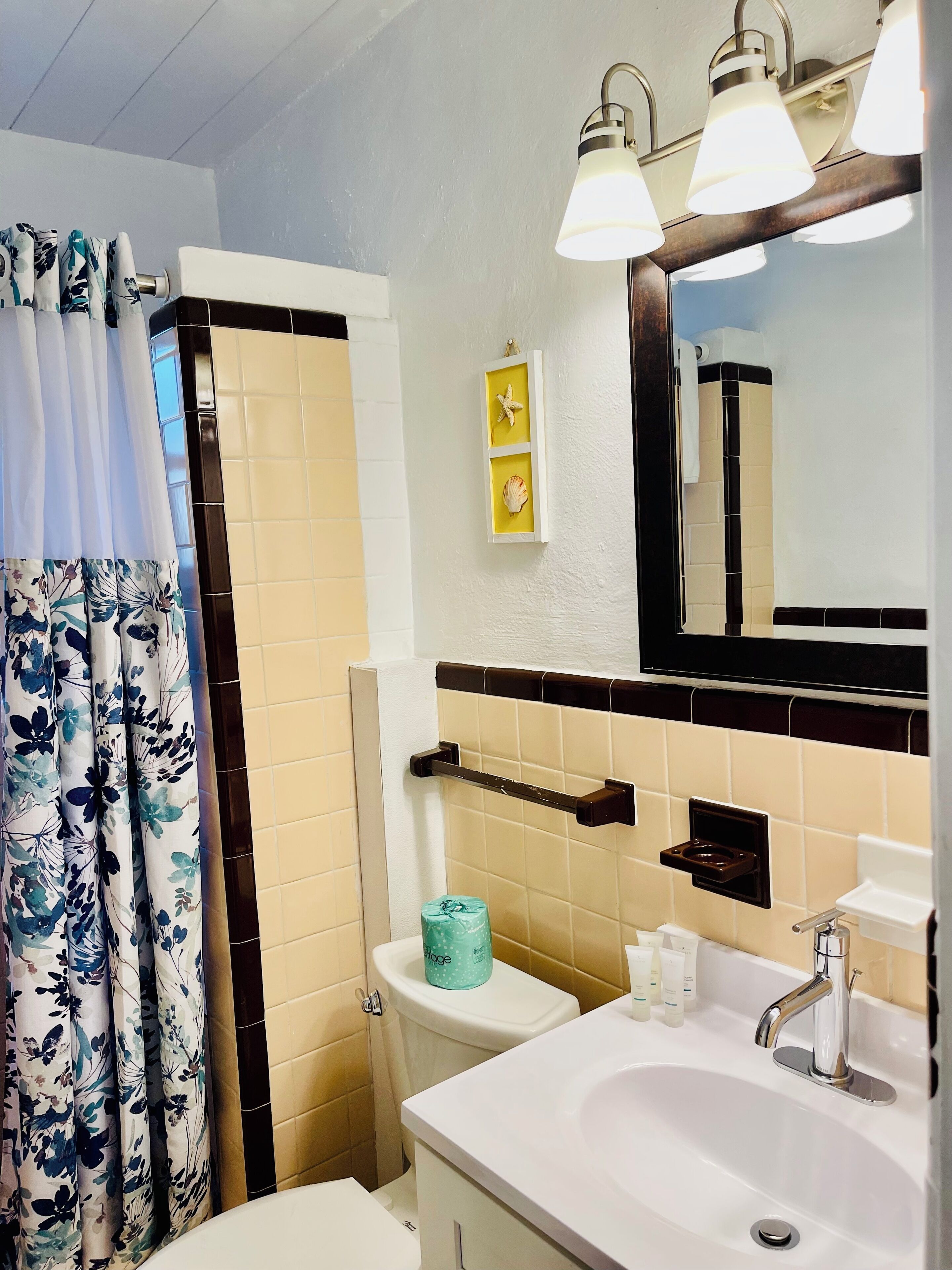 A bathroom with a toilet, sink, mirror, and shower area.