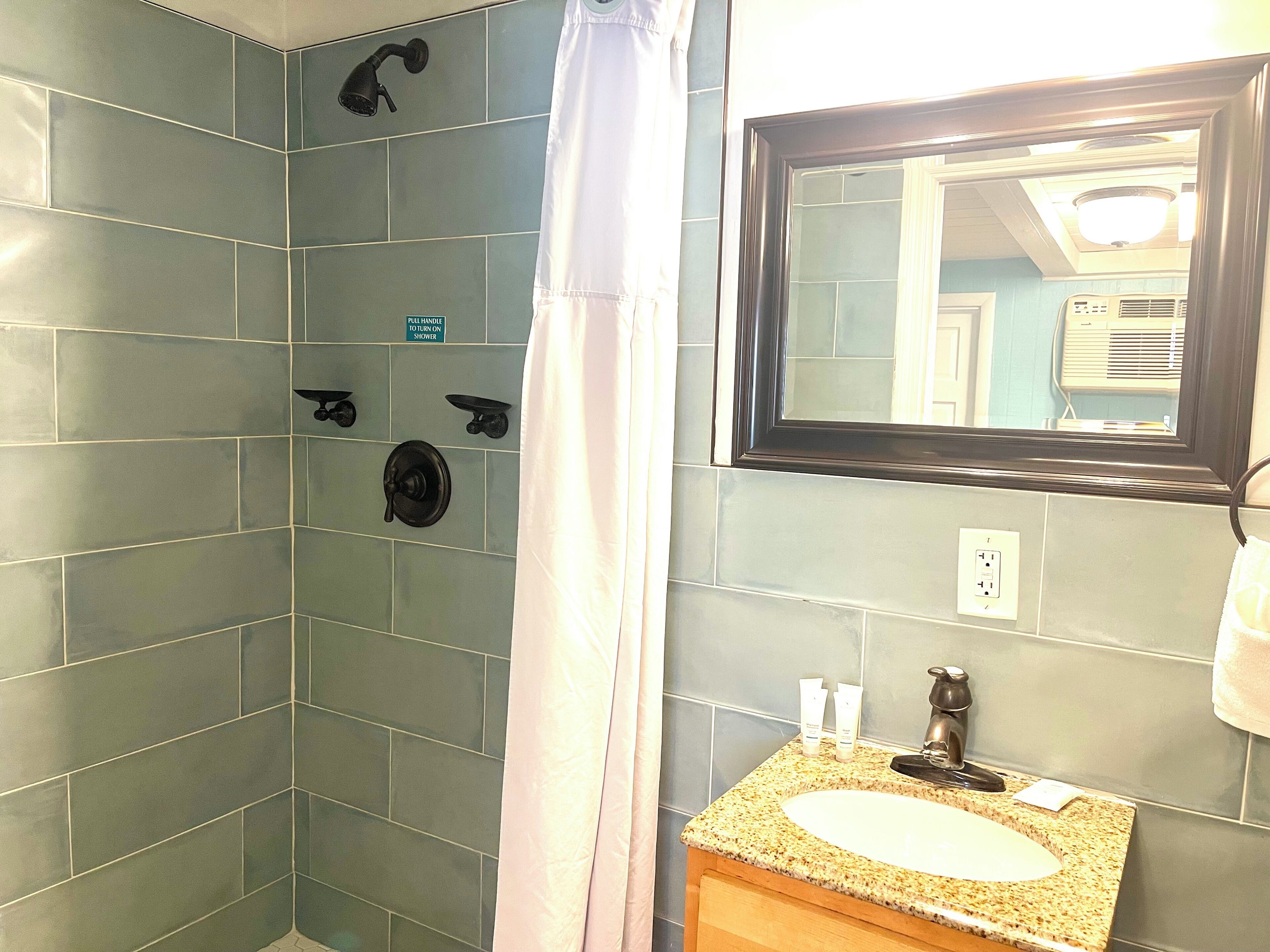 A bathroom with a shower, a sink, and a mirror.