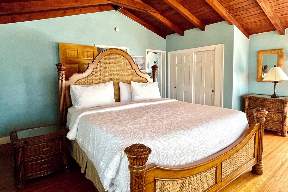 Une chambre à coucher avec un lit en bois, une table de chevet, une commode et une porte.