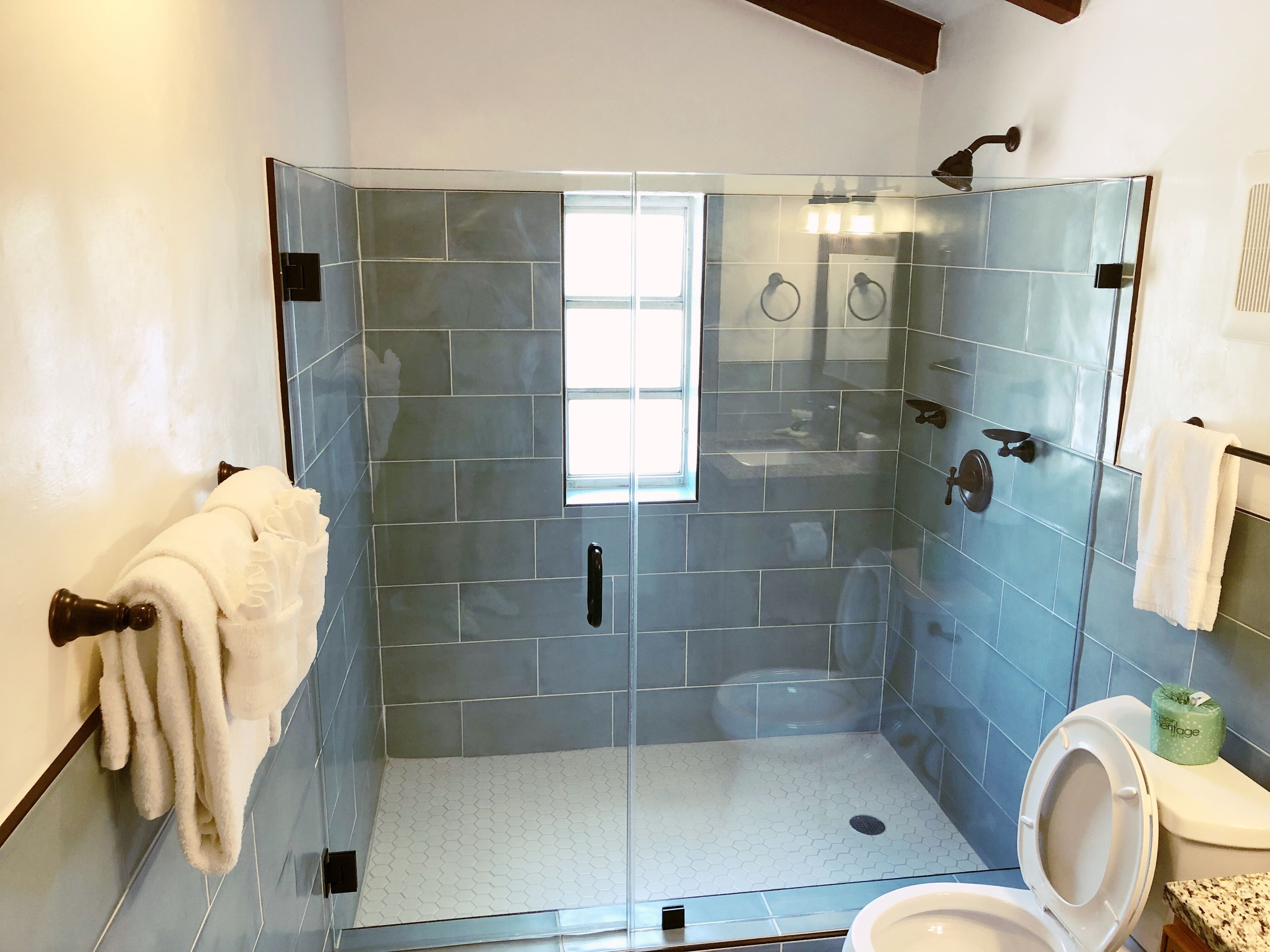 A modern bathroom with a glass-enclosed shower, a toilet, and a sink.