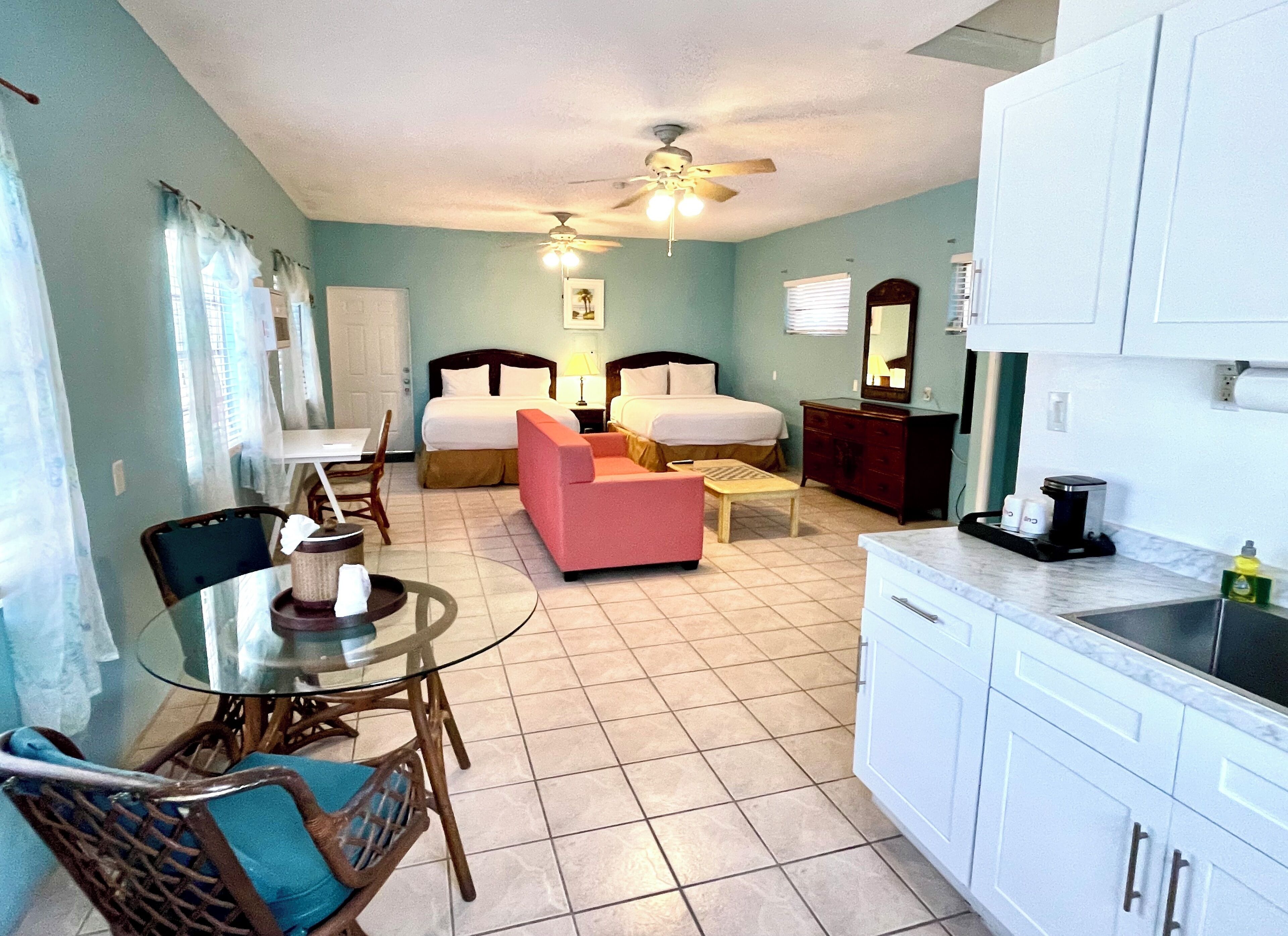 Quarto de hotel com cama, escrivaninha, cadeira, sofá, mesa de jantar e cozinha.