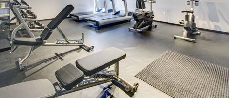 Une salle de sport équipée de tapis de course, d’appareils de musculation et d’un rameur.