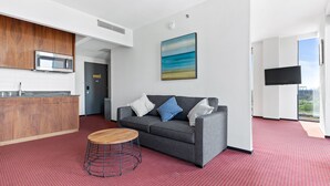 A modern living room with a grey sofa, a wooden coffee table, and a red patterned carpet. - The Parc Hotel (Flushing)