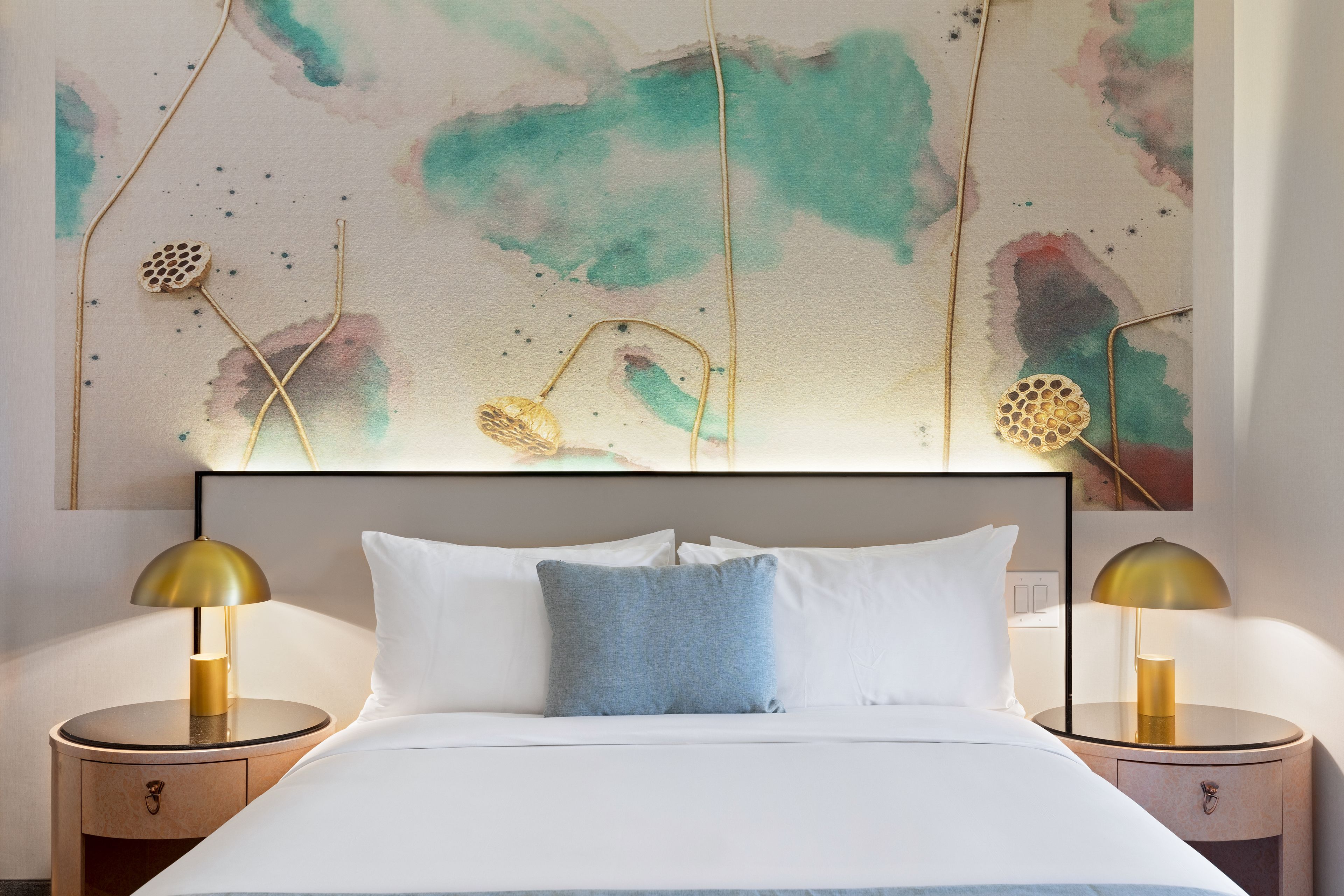 A hotel room with a bed, two bedside tables, and a large abstract painting on the wall.