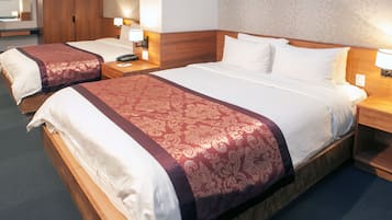 A hotel room with two single beds, each with a wooden headboard, a bedside table with a lamp, and a telephone.