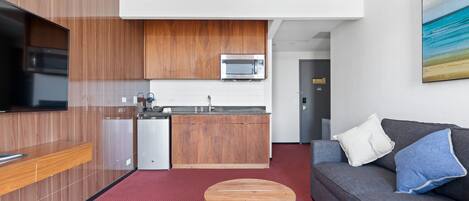 Una cocina moderna con armarios de madera, un microondas integrado y piso cubierto de alfombra roja.