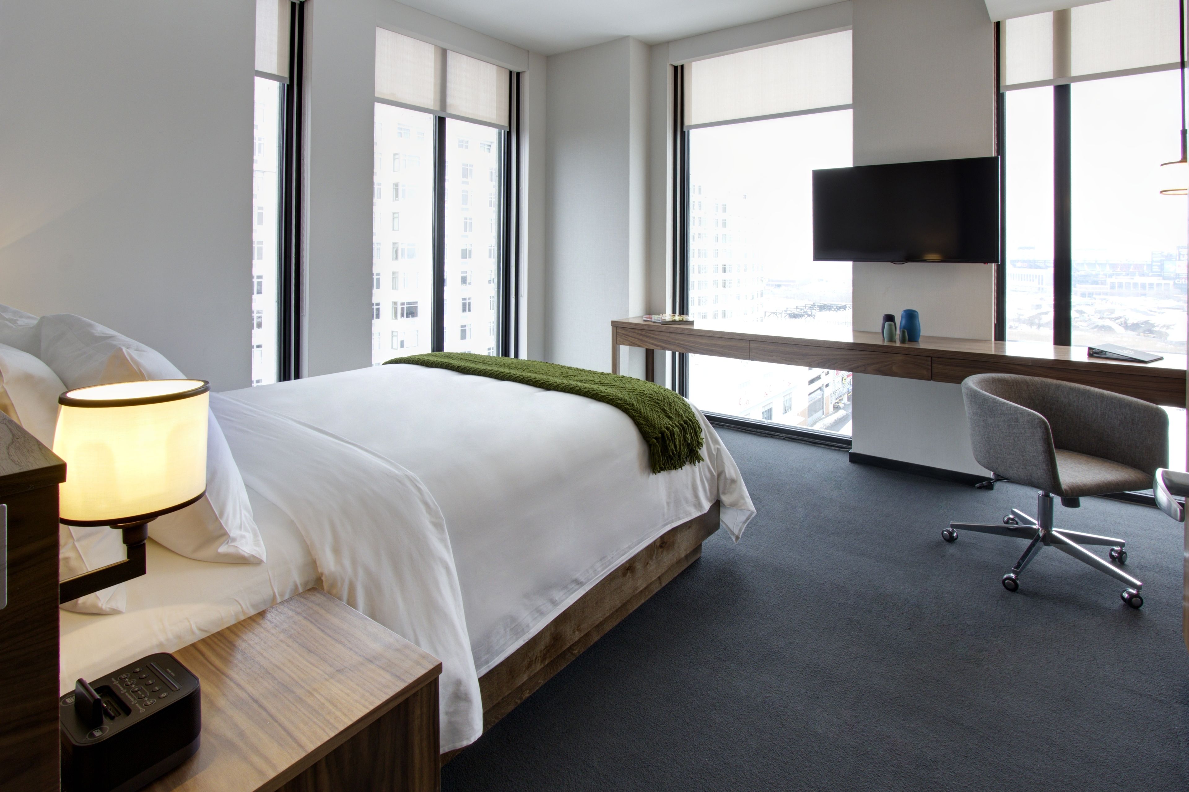 Quarto de hotel moderno com uma cama grande, uma escrivaninha e uma TV.