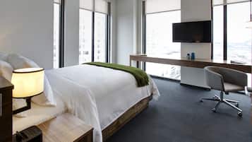 Quarto de hotel moderno com uma cama grande, uma escrivaninha e uma TV.