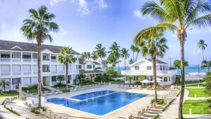 A resort with a large swimming pool surrounded by palm trees and a beach view. - Villa Chiara Las Terrenas (Las Terrenas)
