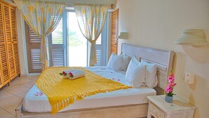 A bedroom with a bed, curtains, a nightstand, and a flower vase. - Villa Chiara Las Terrenas (Las Terrenas)
