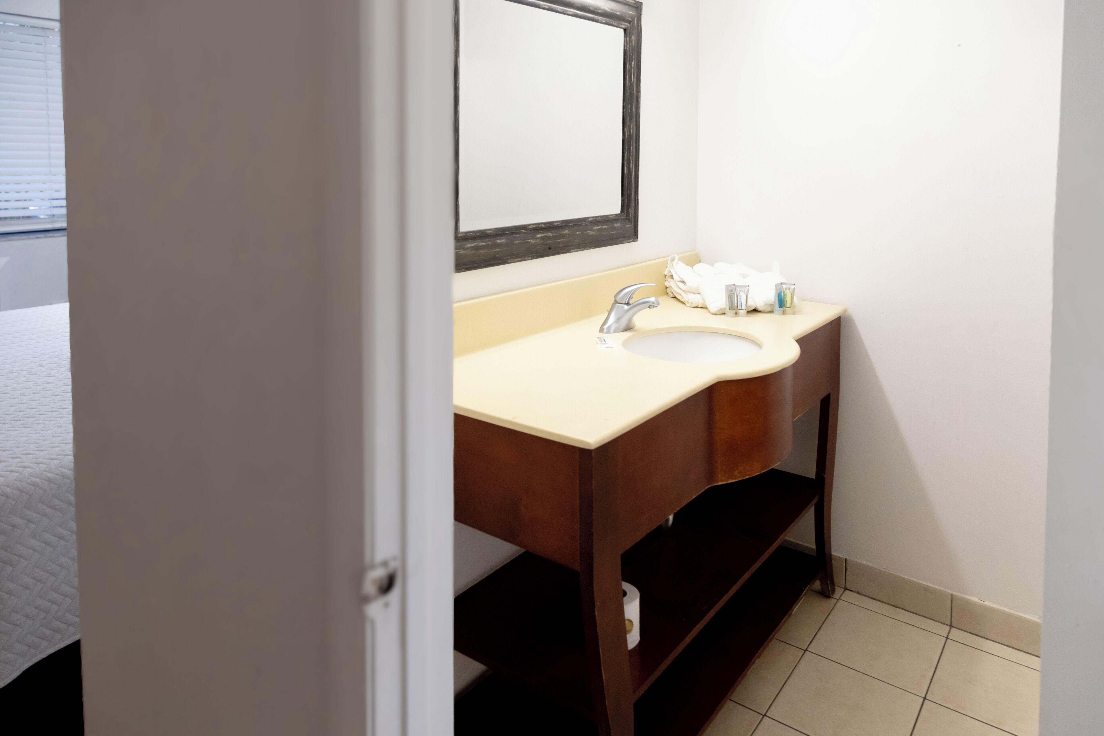 A bathroom with a sink, mirror, and towel dispenser.