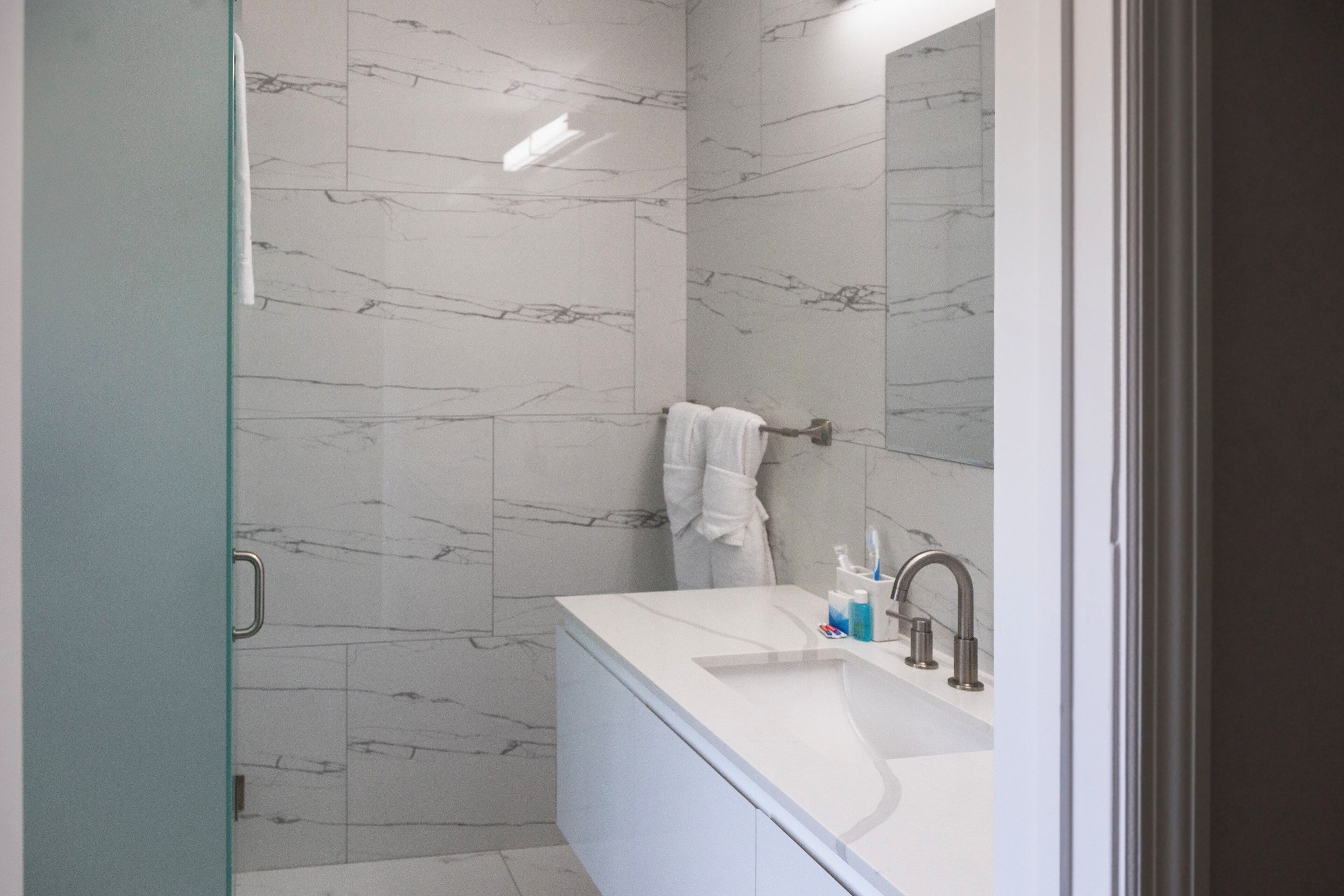 A modern bathroom with a glass shower enclosure, a white vanity with a sink, and a mirror above the vanity.