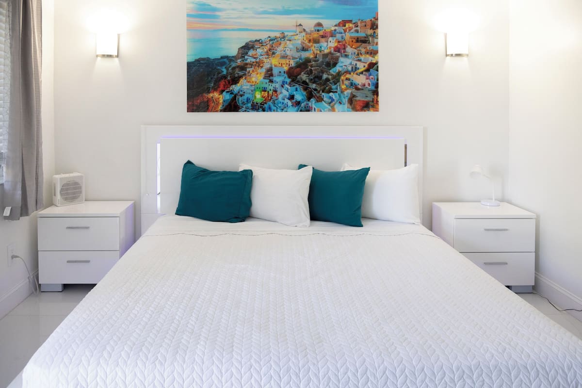 A neatly arranged bedroom with a large bed, two bedside tables, and a wall-mounted painting.