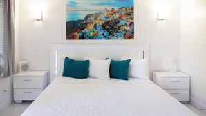 A neatly arranged bedroom with a large bed, two bedside tables, and a wall-mounted painting.