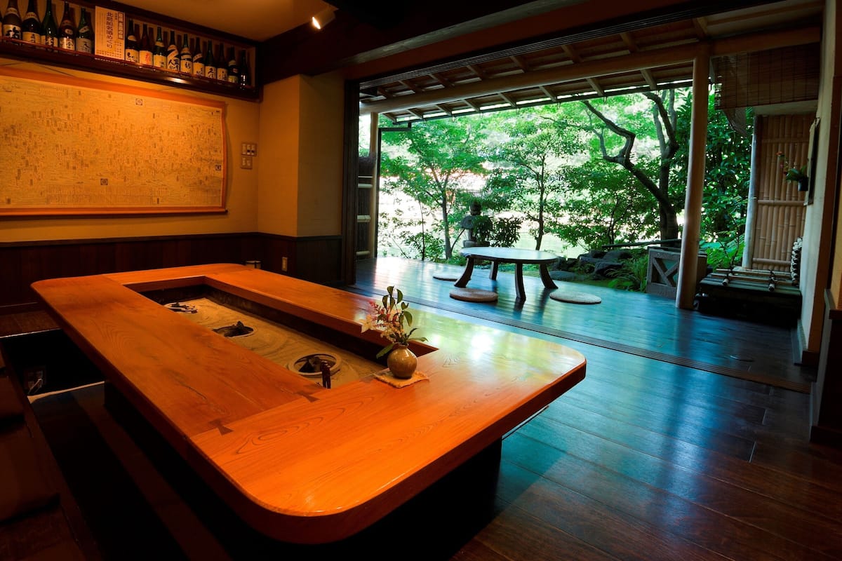 Una mesa de madera con un jarrón de flores, un banco de madera y un mapa grande en la pared.