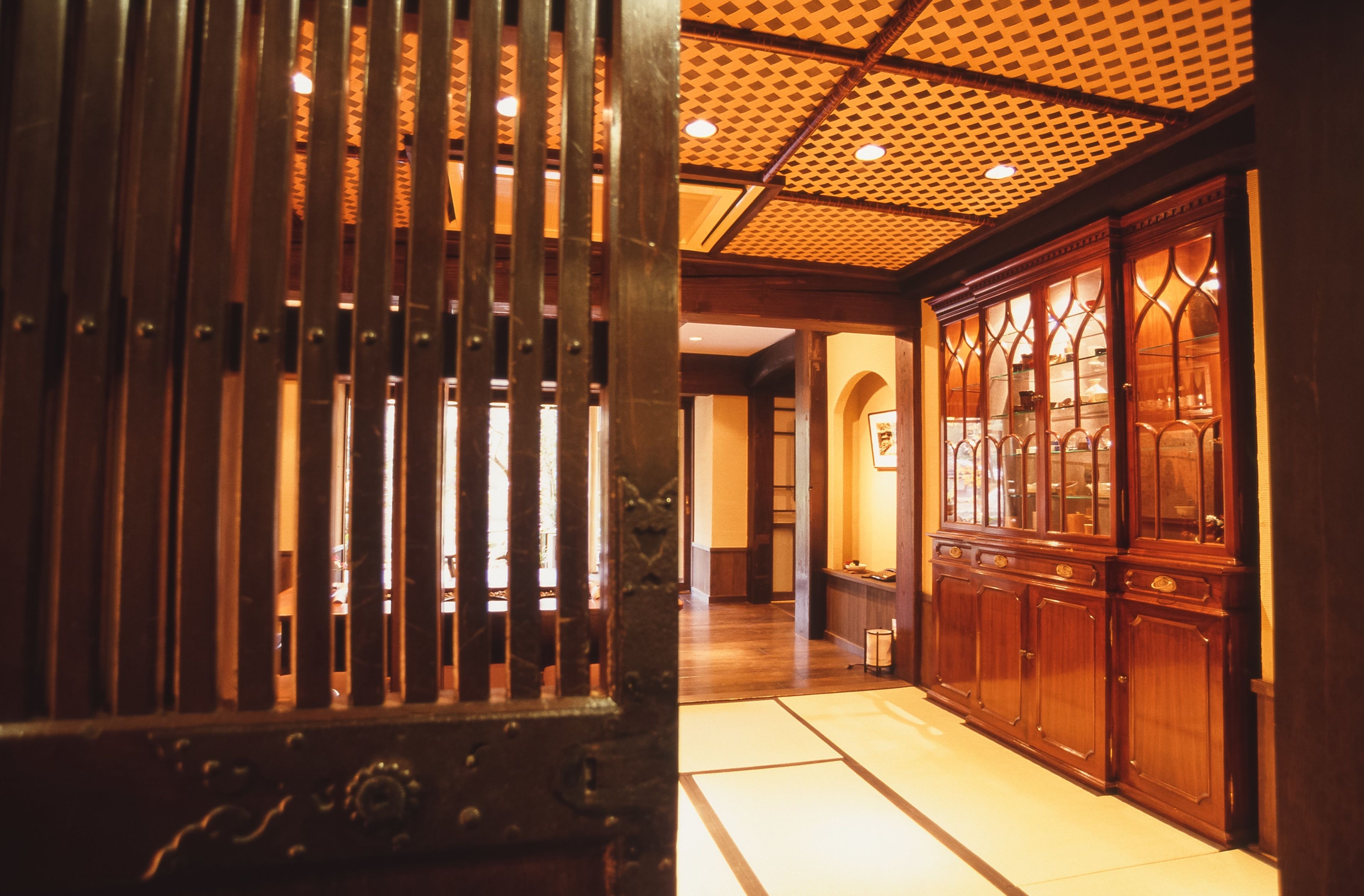 Un intérieur japonais traditionnel avec un sol recouvert de tatamis, des portes coulissantes en bois et un plafond orné de motifs.