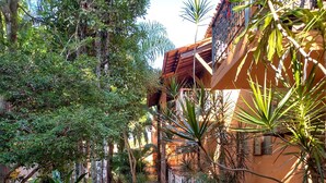 A pathway leading to a building with a balcony, surrounded by lush greenery and palm trees. - Vale Verde Praia Hotel (Porto Seguro)