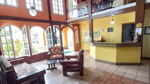 A spacious room with a high ceiling, large windows, and a central seating area with a sofa and chairs. - Vale Verde Praia Hotel (Porto Seguro)