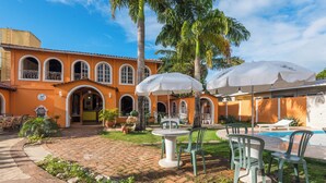 A courtyard with a pool, outdoor seating, and palm trees. - Vale Verde Praia Hotel (Porto Seguro)