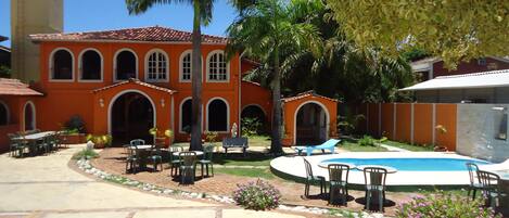 A courtyard with a swimming pool, outdoor seating, and palm trees.