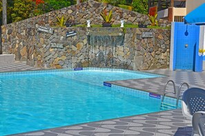 A swimming pool with a stone wall and a waterfall feature. - Hotel Porto das Âncoras (Porto Seguro)