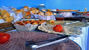 A buffet table with various food items including sliced meats, bread, and vegetables.