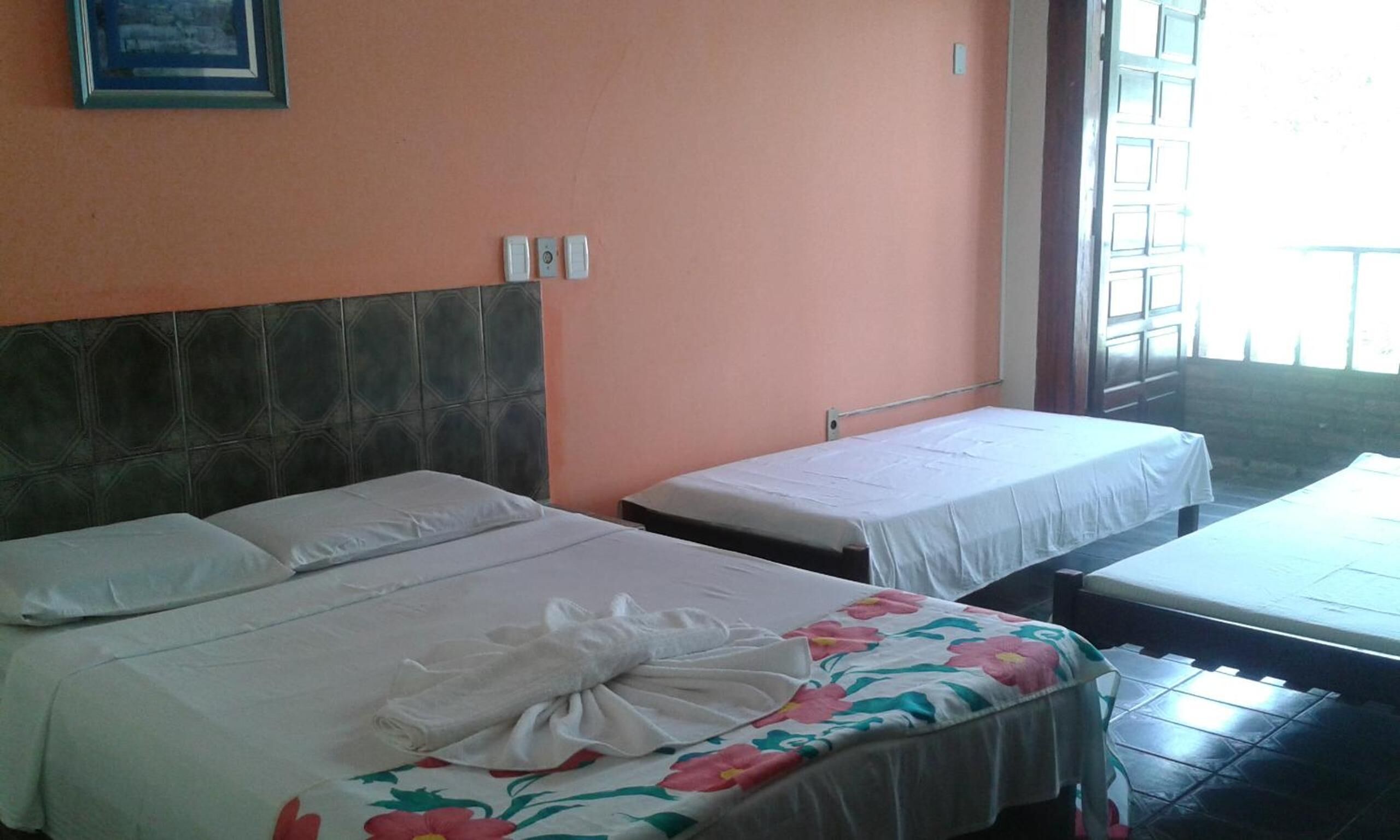 A hotel room with two beds, one with a floral bedspread and the other plain.