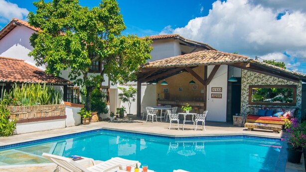 Piscina con sillones de descanso, terraza techada y comedor.