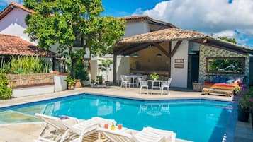 Una piscina al aire libre, sombrillas, sillones reclinables de piscina