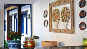 Una habitación con un espejo de marco de madera, platos decorativos y un florero con flores sobre una mesa.