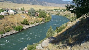 A river flowing through a valley with houses on the banks. - Yellowstone River Suites (Gardiner)