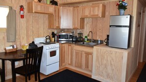 Una cocina compacta con armarios de madera, estufa, microondas, fregadero y refrigerador.