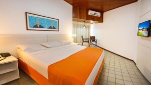A hotel room with a bed, a bedside table with a telephone, a framed picture on the wall, and a television mounted on the wall. - Monte Pascoal Praia Hotel (Porto Seguro)