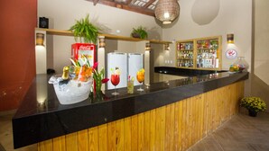 A bar area with a black countertop, ice bucket with drinks, and a shelf with bottles. - Monte Pascoal Praia Hotel (Porto Seguro)