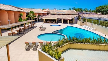 Una piscina al aire libre, sombrillas, sillones reclinables de piscina