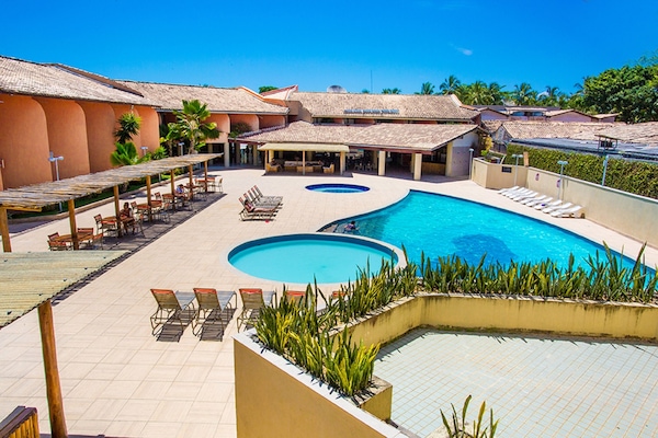 Una piscina al aire libre, sombrillas, tumbonas