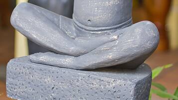 Estátua de uma figura sentada sobre um pedestal.