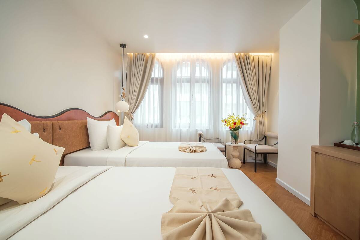 A hotel room with two beds, a sofa, a desk, and a chair.