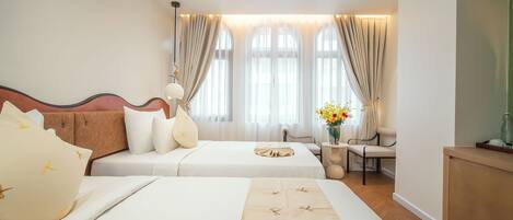 A hotel room with two beds, a sofa, a desk, and a chair.