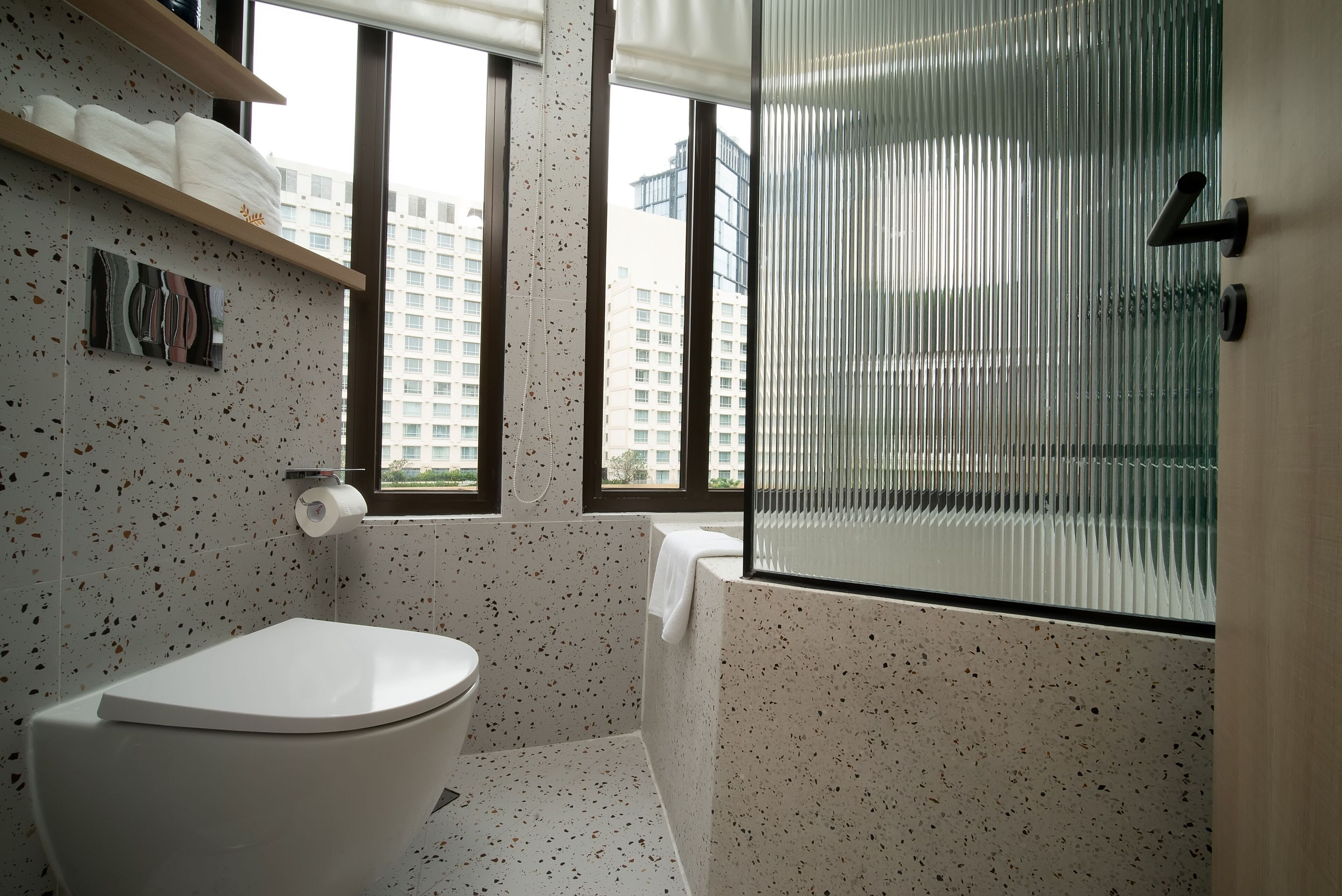 A modern bathroom with a toilet, a towel rack, and a shower area.
