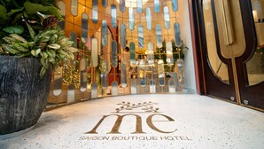 A hotel entrance with a modern design, featuring a logo on the floor and a large potted plant. - Me Saigon Boutique Hotel (Ho Chi Minh City)