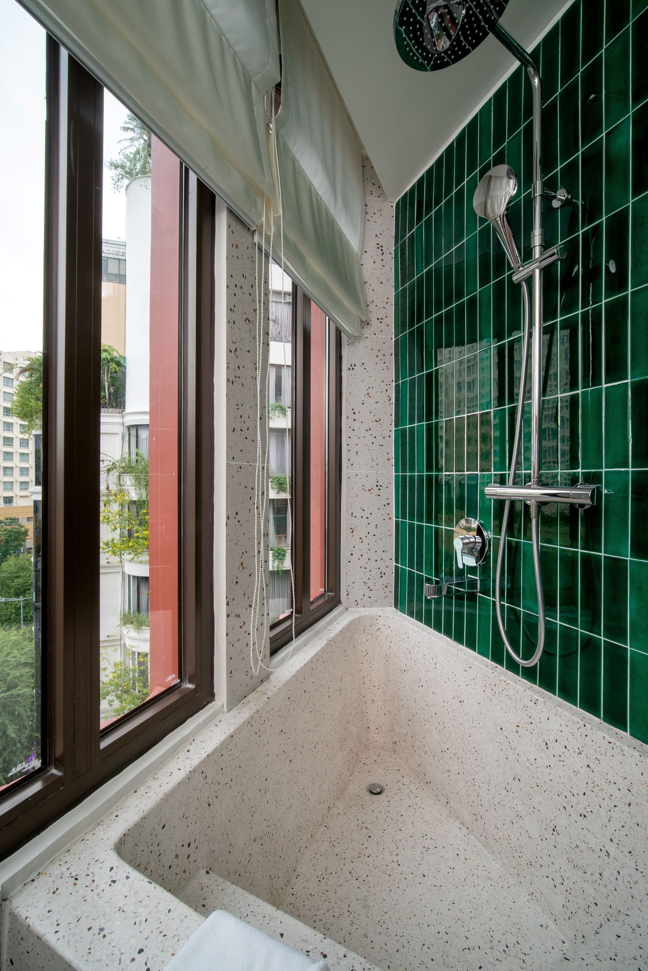 Ein Badezimmer mit Badewanne, Dusche und einem Fenster mit Blick auf Gebäude.