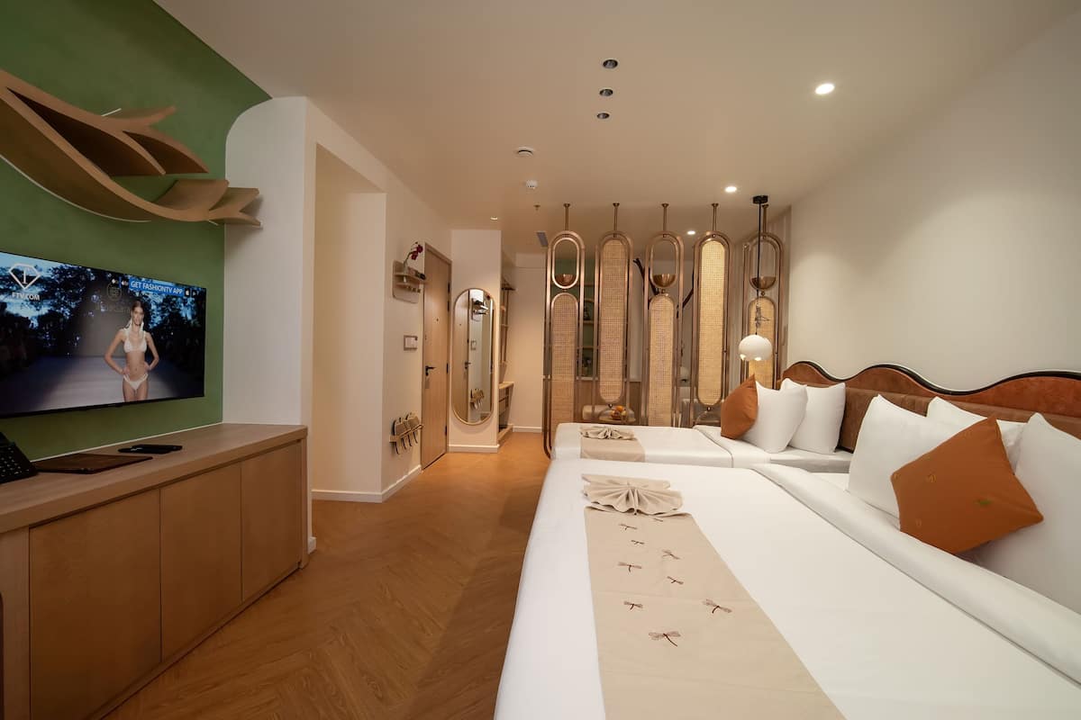 A modern hotel room with a large bed, a TV, and a wooden floor.