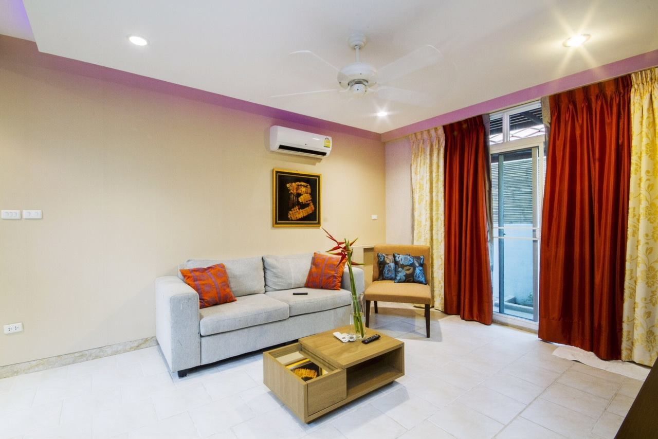 A modern living room with a sofa, a coffee table, a chair, and a window with curtains.