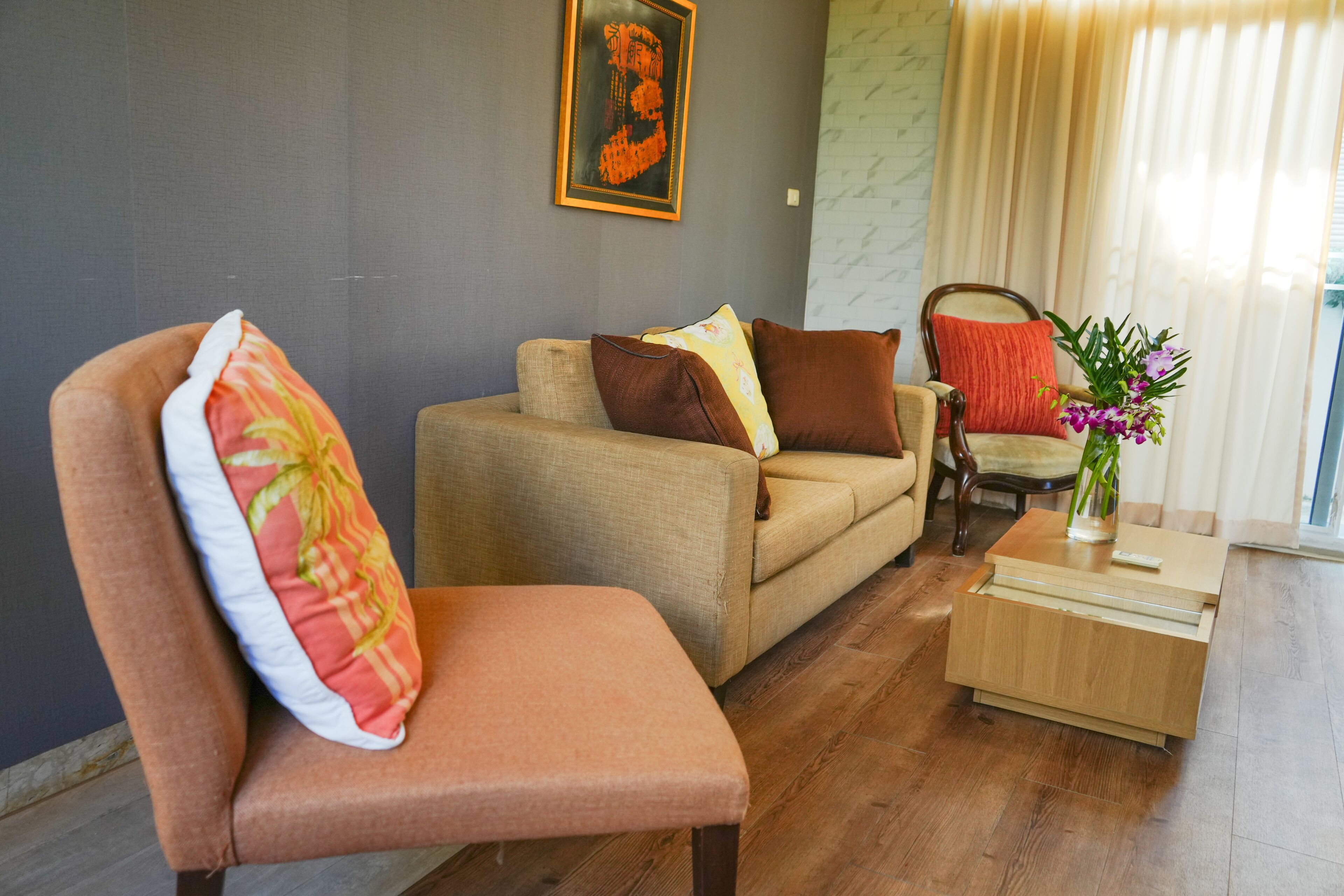 A living room with a sofa, a chair, and a small wooden side table with a vase of flowers.