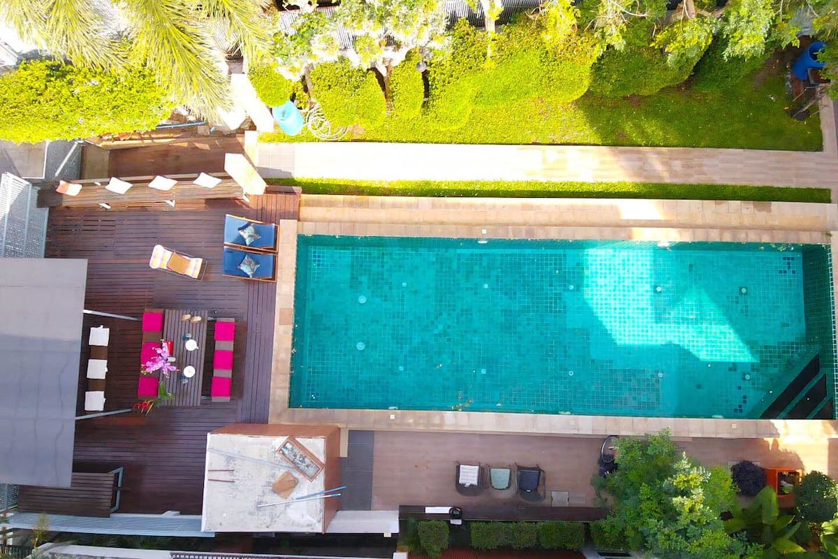 Ein Pool auf dem Dach mit Holzterrasse, Liegestühlen und einer kleinen Sitzecke.